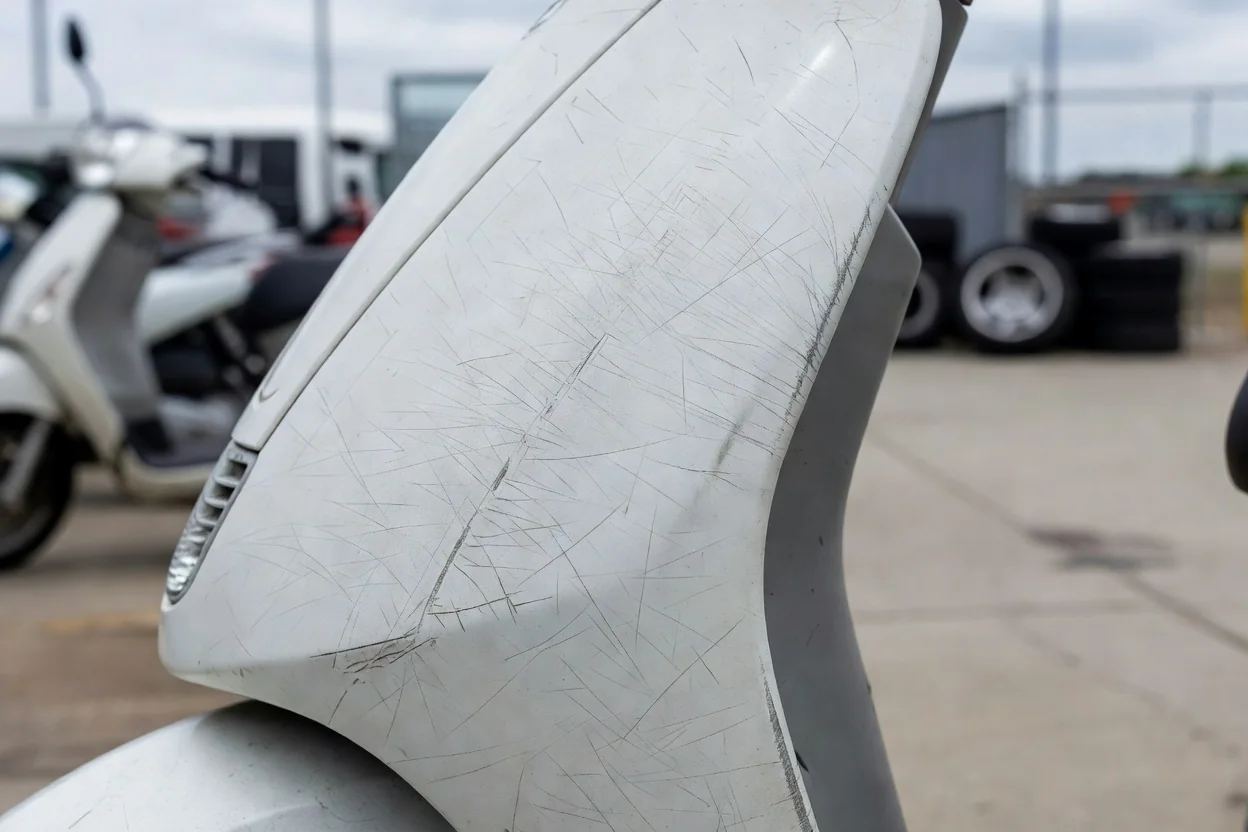Scratched plastic panel on a white rental scooter